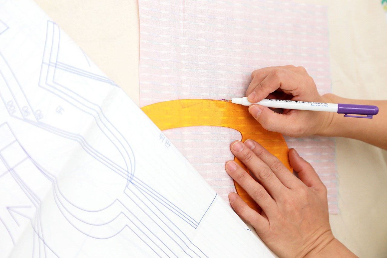Person drafting a pattern onto cloth